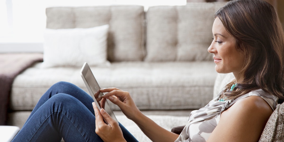 Smiling woman sitting and looking at a tablet